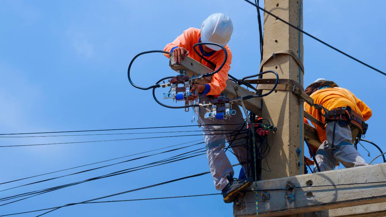 Eletricista trabalhando em painel elétrico de alta tensão com vestimenta de proteção